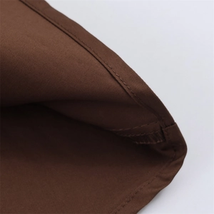 Dettaglio del tessuto twill marrone scuro con cuciture professionali sulla gonna a pieghe