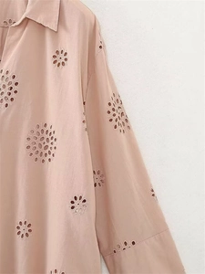 Dettaglio del delicato ricamo sangallo su camicia a maniche lunghe in rosa albicocca tenue