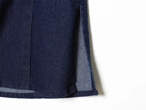 Detailed close-up of dark blue denim corset top hem with fine stitching and side slit