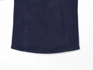 Detailed view of dark indigo denim fabric with vertical seams and precise hem stitching