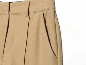Detail of khaki slim-fit trousers showing waist structure and slanted side pockets