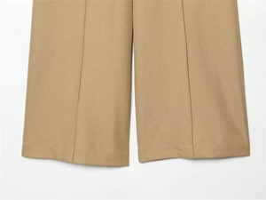 Detail of khaki wide-leg trousers showing crisp center pleats and fine woven fabric texture