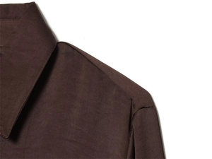 Vue détaillée du col pointu et de la couture d'épaule d'une chemise en satin marron foncé