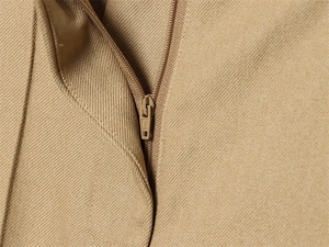 Detailed macro view of matching khaki zipper and twill fabric texture on slim-fit blazer