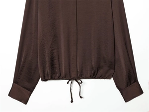 Vue détaillée du tissu satiné marron foncé avec éclat luxueux et cordon de serrage au bas
