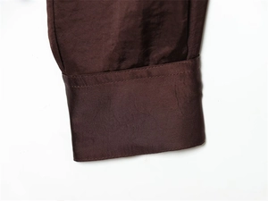 Détail de la manchette de chemise en satin marron avec texture lisse et couture nette