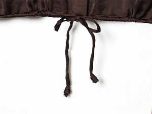 Détail de l'ourlet d'une blouse en satin marron avec cordon de serrage et texture soie