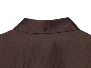Vue macro du col d'une chemise en satin marron foncé montrant une texture soyeuse