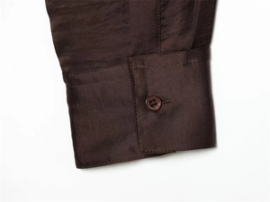 Vue détaillée du poignet d'une chemise en satin chocolat avec un bouton assorti