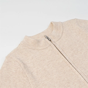 Close-up of beige ribbed knit bodysuit featuring a silver half-zip and mock neckline