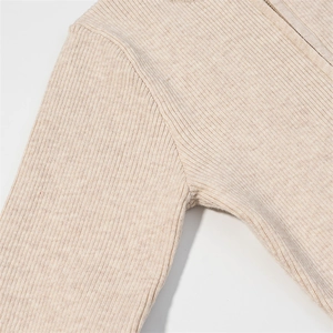 Detail shot of the ribbed knit fabric texture and shoulder seam on the beige bodysuit