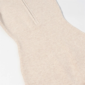 Detailed macro view of beige ribbed knit texture and premium stitching on long sleeve bodysuit