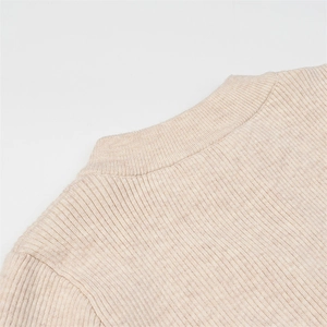 Detailed macro view of the ribbed knit round neckline and shoulder of the beige bodysuit