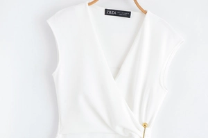 Détail de robe sans manches à col en V avec accessoire épingle de sûreté dorée à la taille