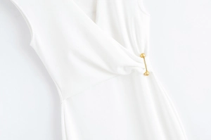 Détail d'une robe blanche sans manches avec boucle dorée et texture en maille côtelée