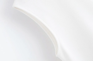 Détail du tissu en sergé fin et des coutures soignées sur une robe blanche à col en V
