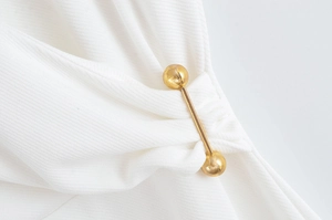 Détail d'une épingle décorative en métal doré sur une robe pour ajuster la taille