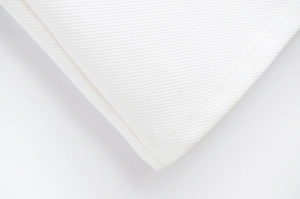 Vue macro détaillée montrant le tissage sergé fin et les coutures précises de la robe blanche