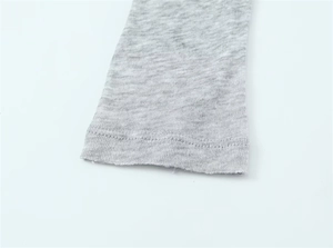 Detail of grey knitted cuff showing precise single-stitch flat seam and soft texture