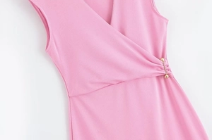 Détail d'une robe rose sans manches à col en V avec plis à la taille et épingle dorée