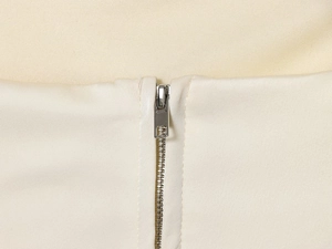 Détail d'une fermeture éclair en métal argenté sur un tissu tissé beige