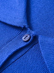 Close-up of blue knit polo shirt collar with fine mesh texture and dark purple button