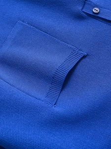 Detailed macro view of royal blue knit fabric featuring chest pocket and matching button