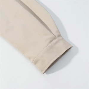 Détail de la couture soignée et du tissu dense sur le poignet de la veste beige