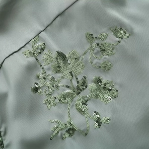Detailed view of intricate floral sequin embroidery on high-quality satin fabric garment