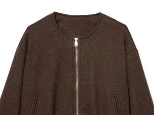 Detailopname van een bruin tweed jasje met een ronde hals en zilveren metalen ritssluiting