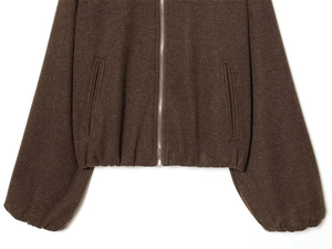 Detailopname van donkerbruin wollen jack met zilveren rits en elastische geribbelde zoom