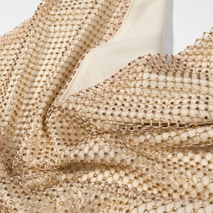 Detail of shimmering golden rhinestones on delicate beige mesh fabric with fine craftsmanship