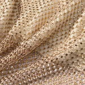 Close-up detail of champagne gold rhinestones on mesh fabric for backless dress