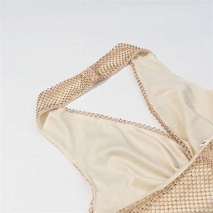 Close-up of cream halter dress with intricate hollow mesh and gold metallic beadwork