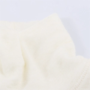 Dettaglio macro della trama a maglia fine e del tessuto bianco avorio della t-shirt asimmetrica
