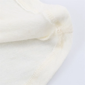 Dettaglio del tessuto in maglia bianco crema con cuciture precise su top asimmetrico
