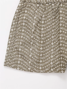 Detailed macro view of olive green shorts featuring white floral embroidery and woven texture
