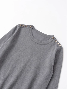 Detail of grey crewneck knit sweater with elegant gold button accents on shoulders