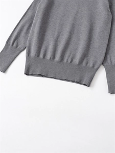Detailed view of the ribbed cuffs and hem on this grey knit long sleeve sweater