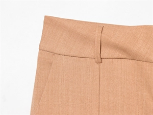Détails d'un pantalon marron clair montrant les passants et poches latérales