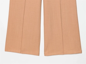 Détail du pantalon de costume camel avec pli central précis et finitions des coutures