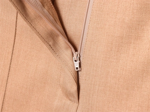 Gros plan sur la fermeture éclair invisible et le tissu camel de qualité du pantalon