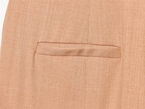 Gros plan d'une poche passepoilée sur un pantalon de costume beige à texture sergé