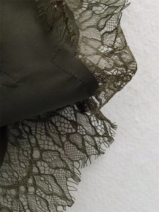 Detailweergave van olijfgroene stof met verfijnde wimperkant langs de zoom van het kledingstuk
