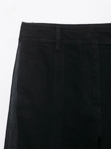 Détail de pantalon noir à taille haute avec garniture de franges argentées sur le côté