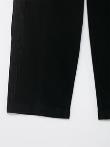 Gros plan détaillé sur les longues franges et le tissu noir de ce pantalon élégant