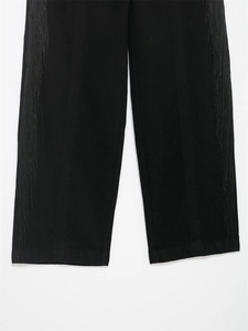 Gros plan détaillé du pantalon noir avec de longues franges sur les coutures latérales