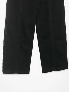 Détail de pantalon droit en denim noir avec finitions frangées et surpiqûres