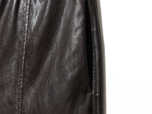 Detailed macro view of dark brown faux leather texture and reinforced pocket stitching