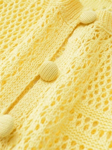 Detailed macro of bright yellow hollow crochet knit fabric with matching woven buttons